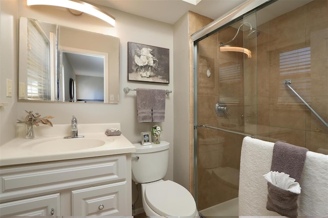 bathroom featuring a shower stall, toilet, and vanity