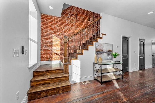 stairway with brick wall and wood-type flooring