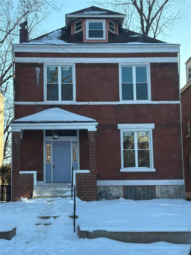 view of front facade featuring brick siding and a chimney