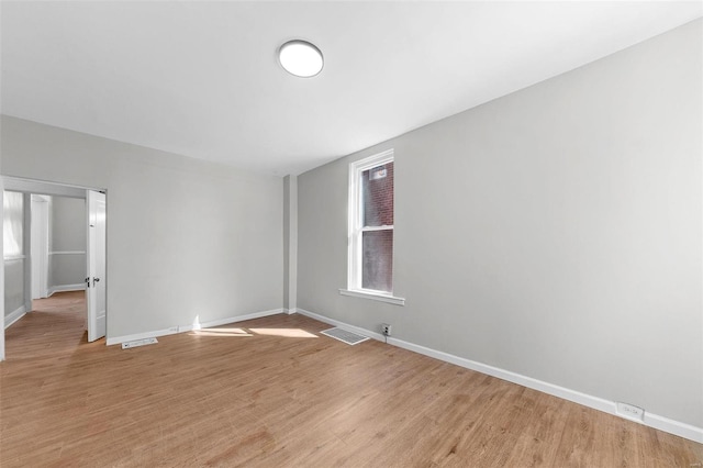 unfurnished room with light wood-style floors, visible vents, and baseboards