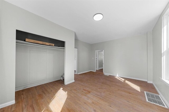unfurnished bedroom with light wood-style flooring, a closet, visible vents, and baseboards