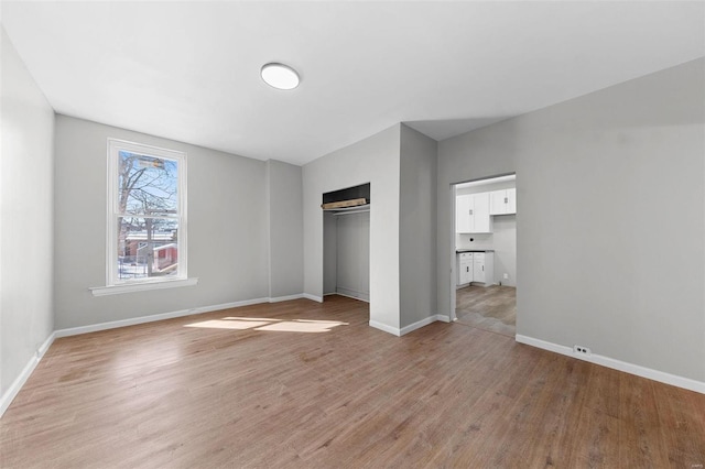 unfurnished bedroom with light wood finished floors, baseboards, and a closet