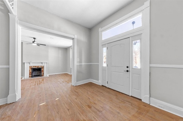 entryway featuring light wood-style floors, baseboards, and a fireplace with raised hearth