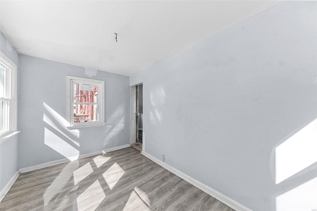 spare room with baseboards and light wood finished floors