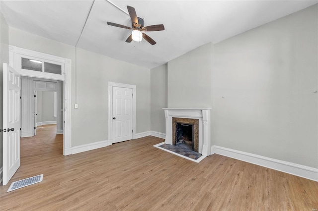 unfurnished living room with baseboards, visible vents, ceiling fan, light wood-style floors, and a fireplace
