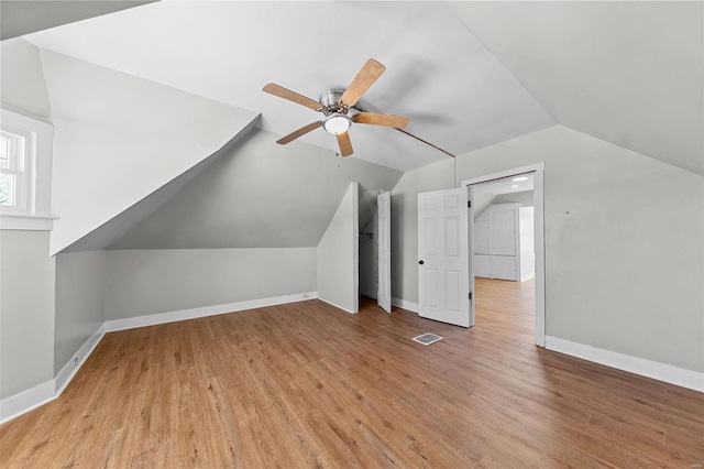 bonus room with lofted ceiling, visible vents, baseboards, a ceiling fan, and light wood-style floors