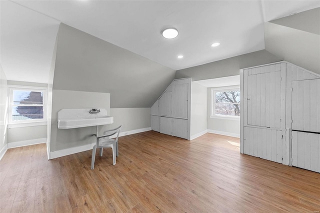 bonus room with vaulted ceiling, a sink, light wood-style flooring, and baseboards
