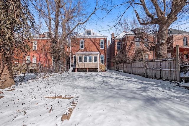 snow covered rear of property with fence