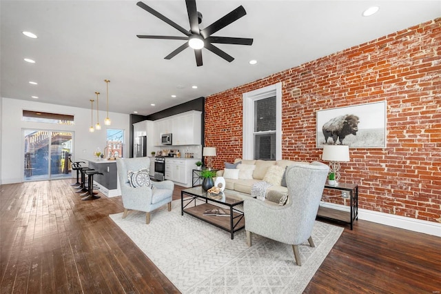 living room featuring ceiling fan, brick wall, and hardwood / wood-style floors