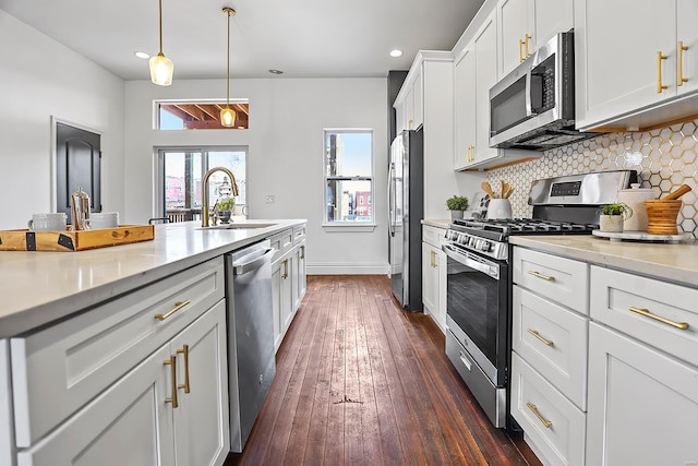 kitchen featuring stainless steel appliances, decorative light fixtures, sink, tasteful backsplash, and white cabinets