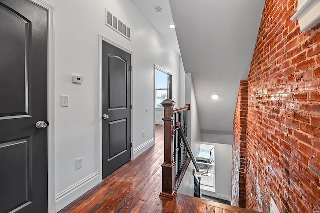 hallway featuring brick wall, vaulted ceiling, and dark hardwood / wood-style floors