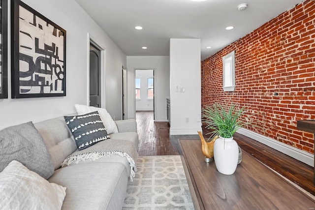 living room featuring dark hardwood / wood-style flooring and brick wall