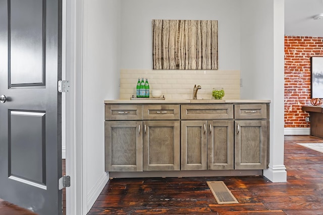 bar with brick wall, sink, dark hardwood / wood-style floors, and decorative backsplash