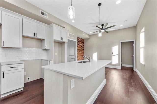 kitchen with an island with sink, decorative light fixtures, decorative backsplash, sink, and white cabinetry