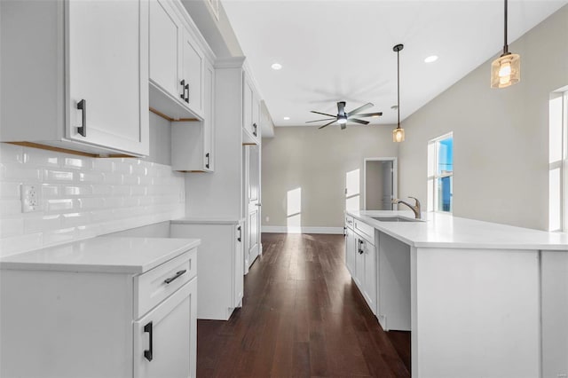 kitchen featuring sink, ceiling fan, white cabinets, hanging light fixtures, and an island with sink