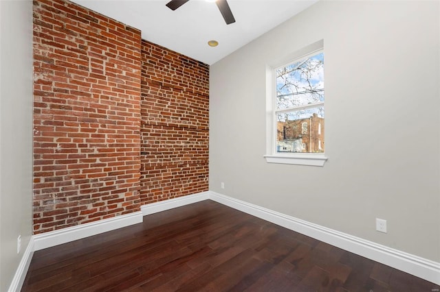 unfurnished room featuring ceiling fan, hardwood / wood-style flooring, and brick wall