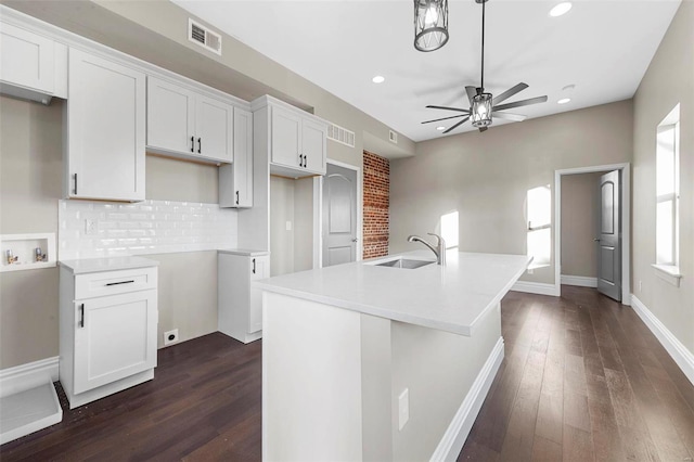 kitchen featuring sink, a center island with sink, dark wood-type flooring, and white cabinetry