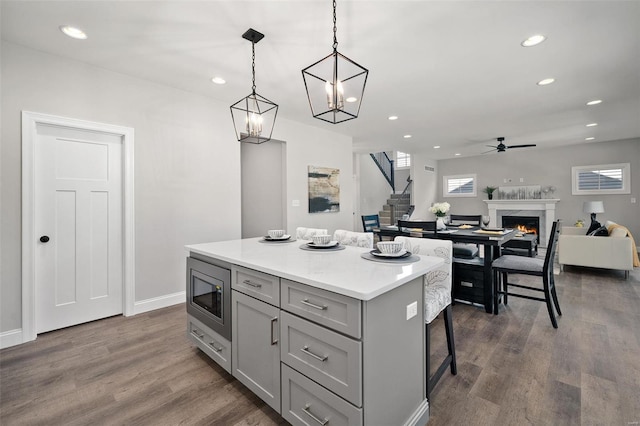 kitchen featuring a kitchen island, a high end fireplace, gray cabinets, dark wood-style floors, and stainless steel microwave