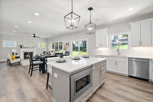 kitchen featuring appliances with stainless steel finishes, a premium fireplace, a sink, and light wood-style floors