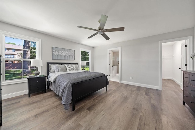 bedroom with ensuite bathroom, wood finished floors, a ceiling fan, and baseboards