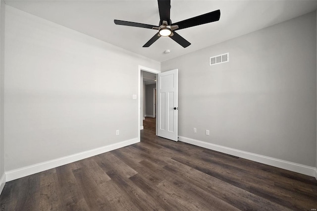 unfurnished room featuring a ceiling fan, visible vents, dark wood finished floors, and baseboards