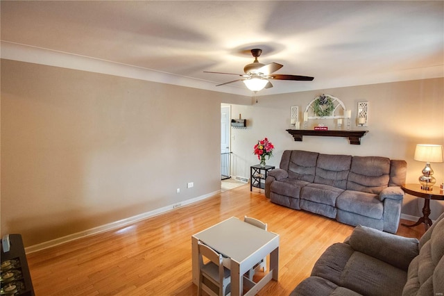 living room with wood finished floors, a ceiling fan, and baseboards