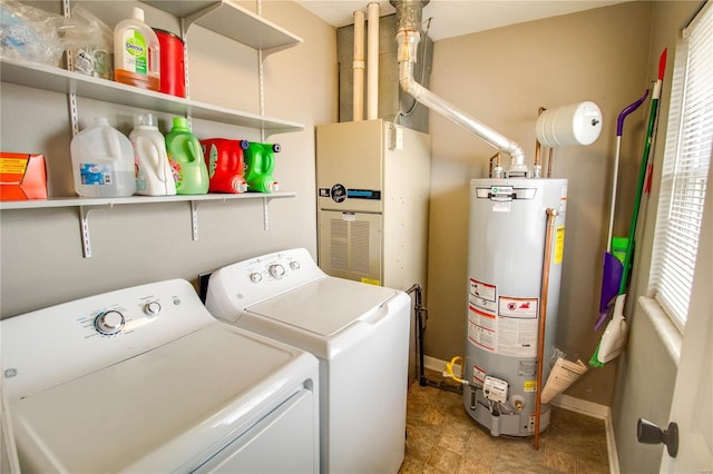 clothes washing area with water heater, laundry area, washing machine and dryer, and baseboards