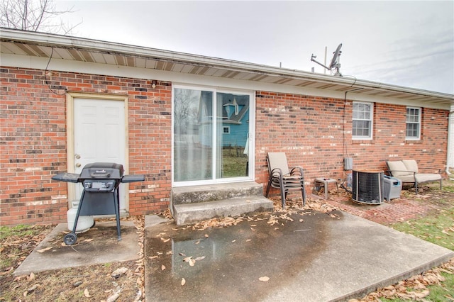 rear view of house with entry steps, brick siding, a patio, and central air condition unit