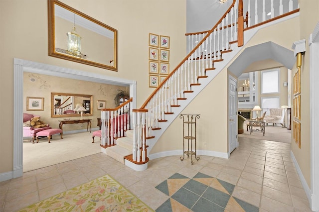 stairway featuring baseboards, a high ceiling, a chandelier, and tile patterned flooring