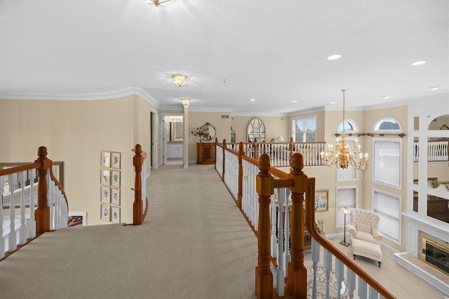 hallway with ornamental molding, an inviting chandelier, an upstairs landing, and light colored carpet