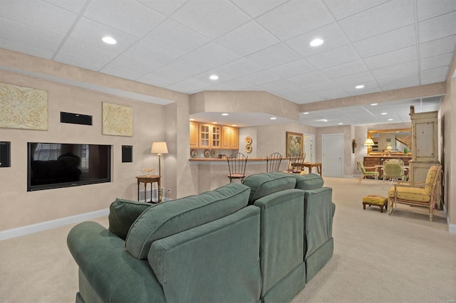 living room featuring baseboards, a drop ceiling, recessed lighting, and light colored carpet