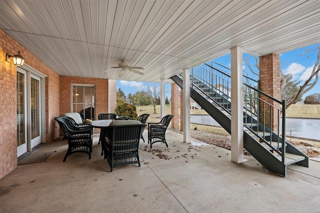 view of patio / terrace with outdoor dining space, stairway, a water view, and a ceiling fan