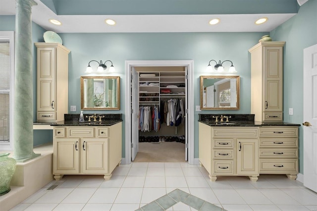 bathroom with ornate columns, two vanities, a sink, and tile patterned floors