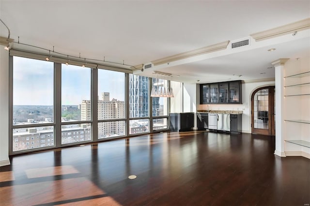 unfurnished living room with a city view, dark wood-type flooring, visible vents, expansive windows, and ornate columns