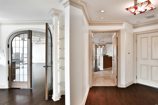 hall featuring ornamental molding, dark wood-style flooring, visible vents, and decorative columns