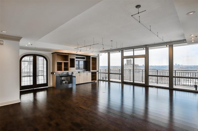 unfurnished living room featuring a wealth of natural light, a wall of windows, wood finished floors, and french doors