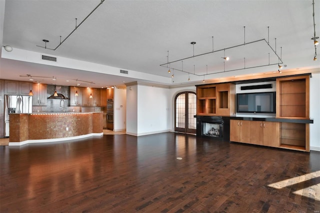 kitchen with dark wood-type flooring, visible vents, wall chimney range hood, and stainless steel fridge with ice dispenser