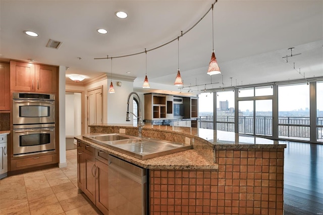 kitchen featuring a kitchen island with sink, recessed lighting, stainless steel appliances, open floor plan, and pendant lighting