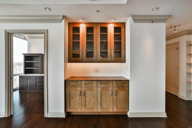 kitchen featuring baseboards, dark wood-style floors, glass insert cabinets, brown cabinets, and recessed lighting