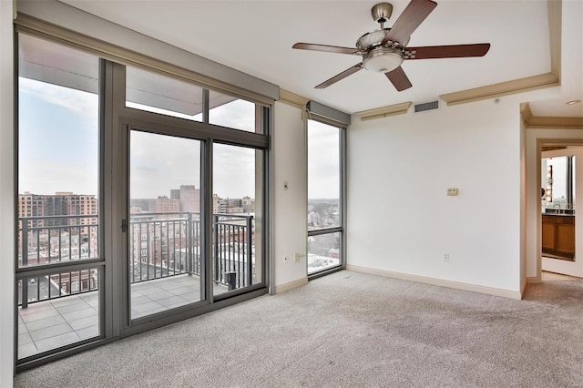 unfurnished room with visible vents, baseboards, ceiling fan, carpet, and a city view