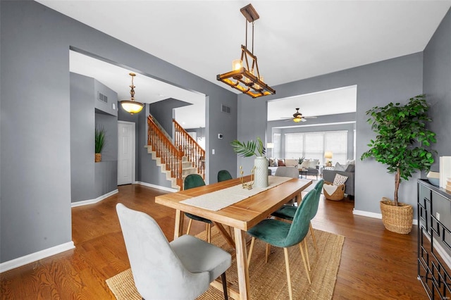 dining space with baseboards, visible vents, stairway, and wood finished floors