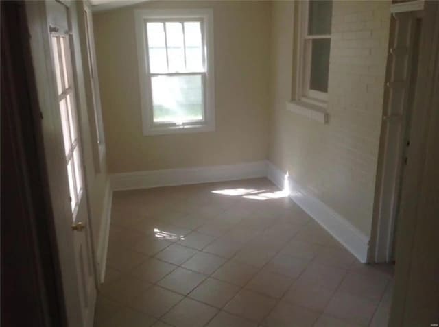 empty room with light tile patterned floors and baseboards