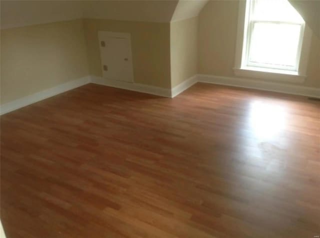 bonus room with vaulted ceiling, light wood-style flooring, and baseboards