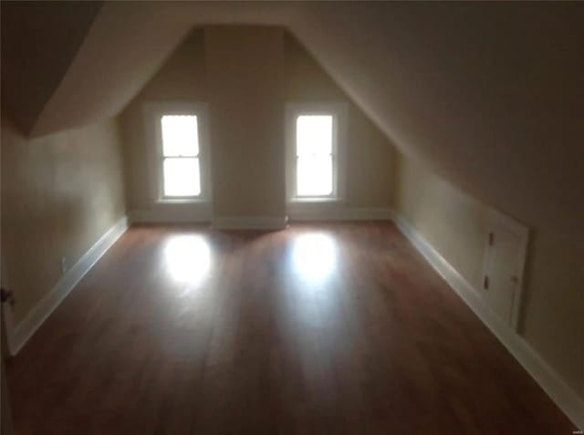 bonus room with baseboards, vaulted ceiling, and light wood finished floors