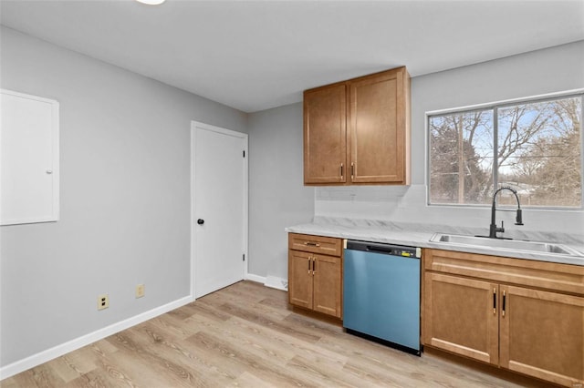 kitchen with a sink, light wood-style flooring, light countertops, and stainless steel dishwasher