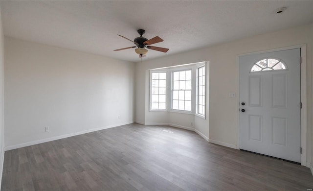 entryway with ceiling fan, a textured ceiling, baseboards, and wood finished floors