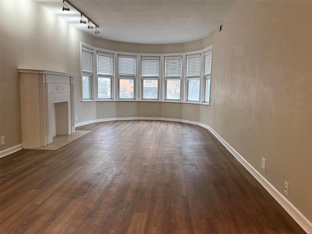 unfurnished living room with dark wood finished floors, a fireplace, and baseboards