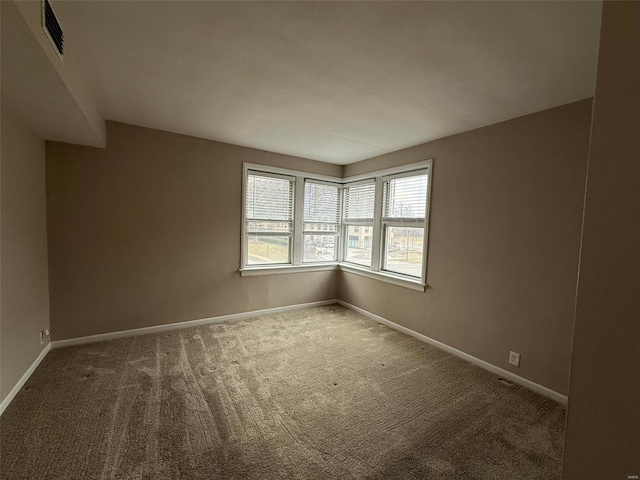 carpeted spare room featuring visible vents and baseboards