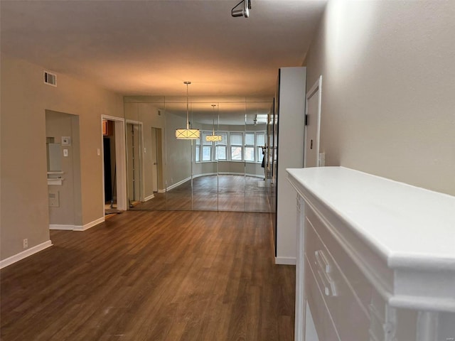 hallway featuring visible vents, baseboards, and dark wood-style flooring