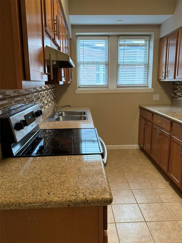 kitchen with stainless steel electric range oven, brown cabinetry, baseboards, a sink, and tasteful backsplash